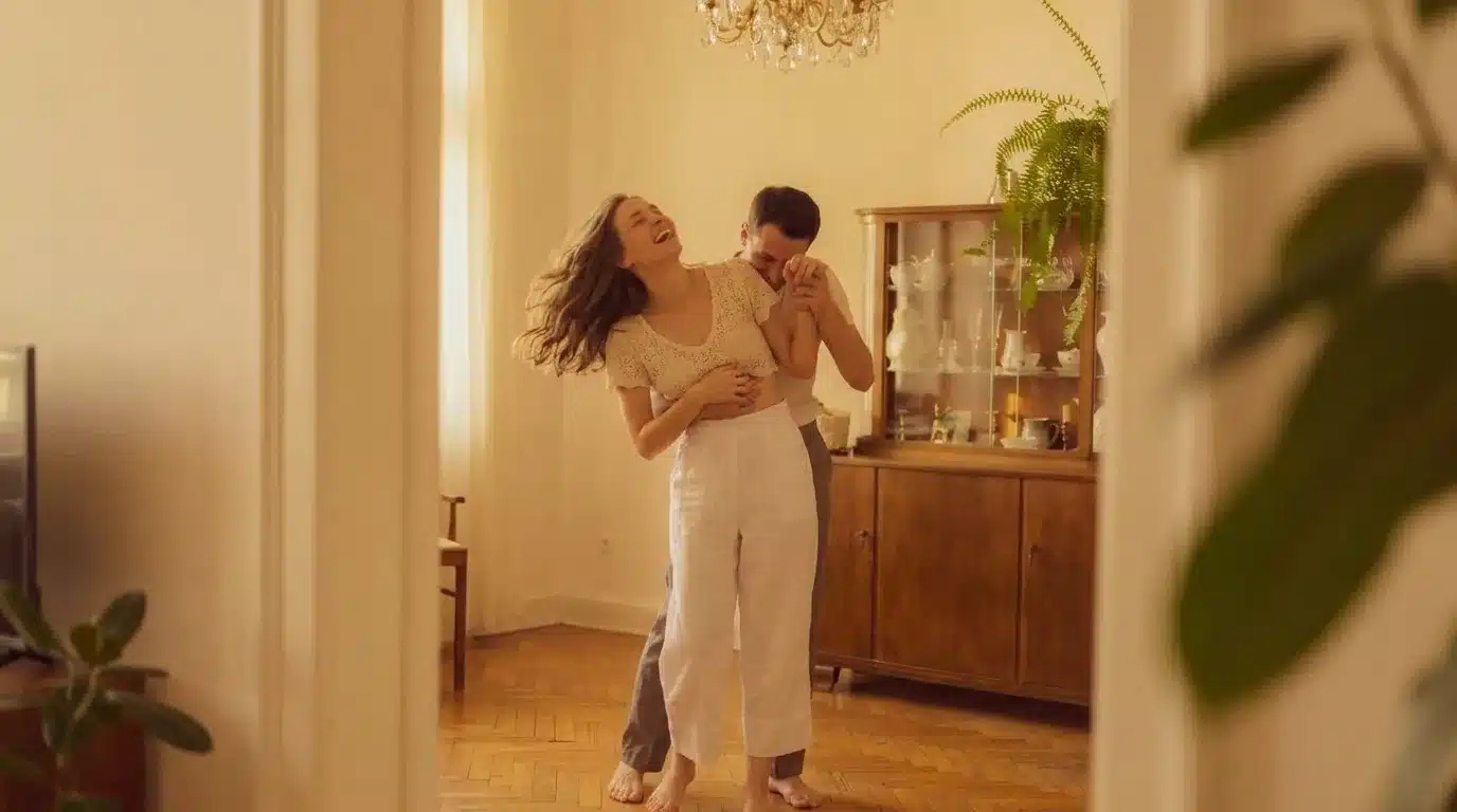 A joyful couple laughing and embracing in a sunlit room, sharing an intimate moment that reflects warmth and connection