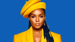 Janelle Monáe wears a yellow beret and coat against a blue background.