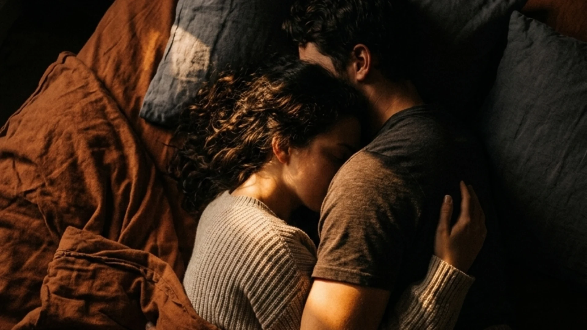 A couple lying closely in bed, embracing each other, sharing a quiet, intimate moment of connection