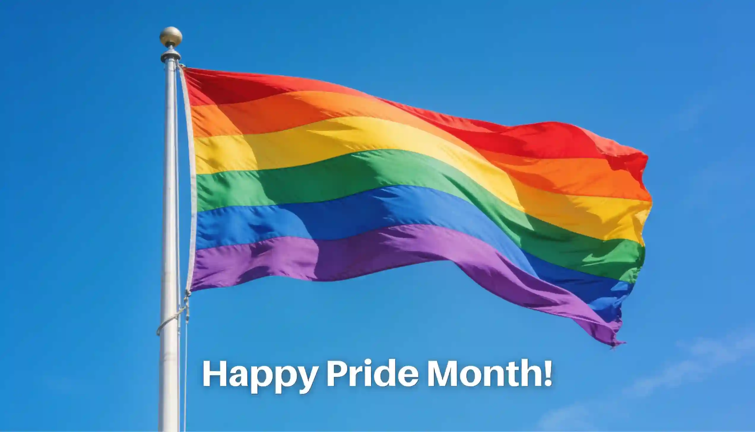Rainbow pride flag waving on a flagpole against a clear blue sky with "Happy Pride Month!" text.