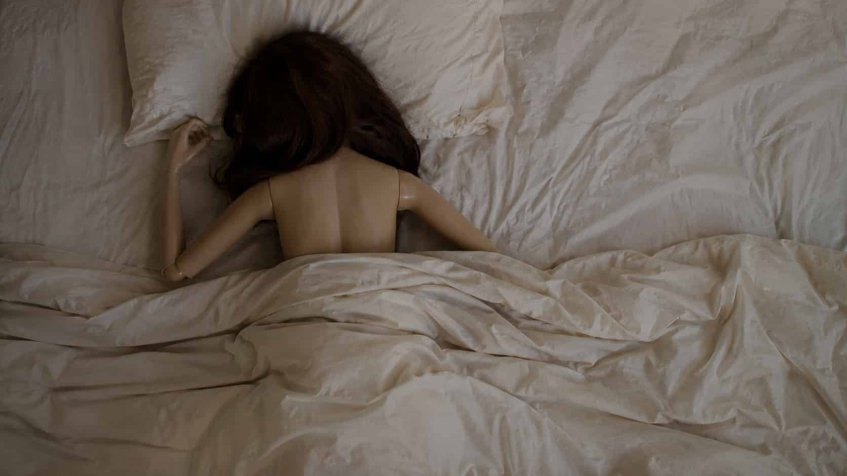 sex doll diy showing a human sized doll half hidden under bedsheets with bare back in overhead view